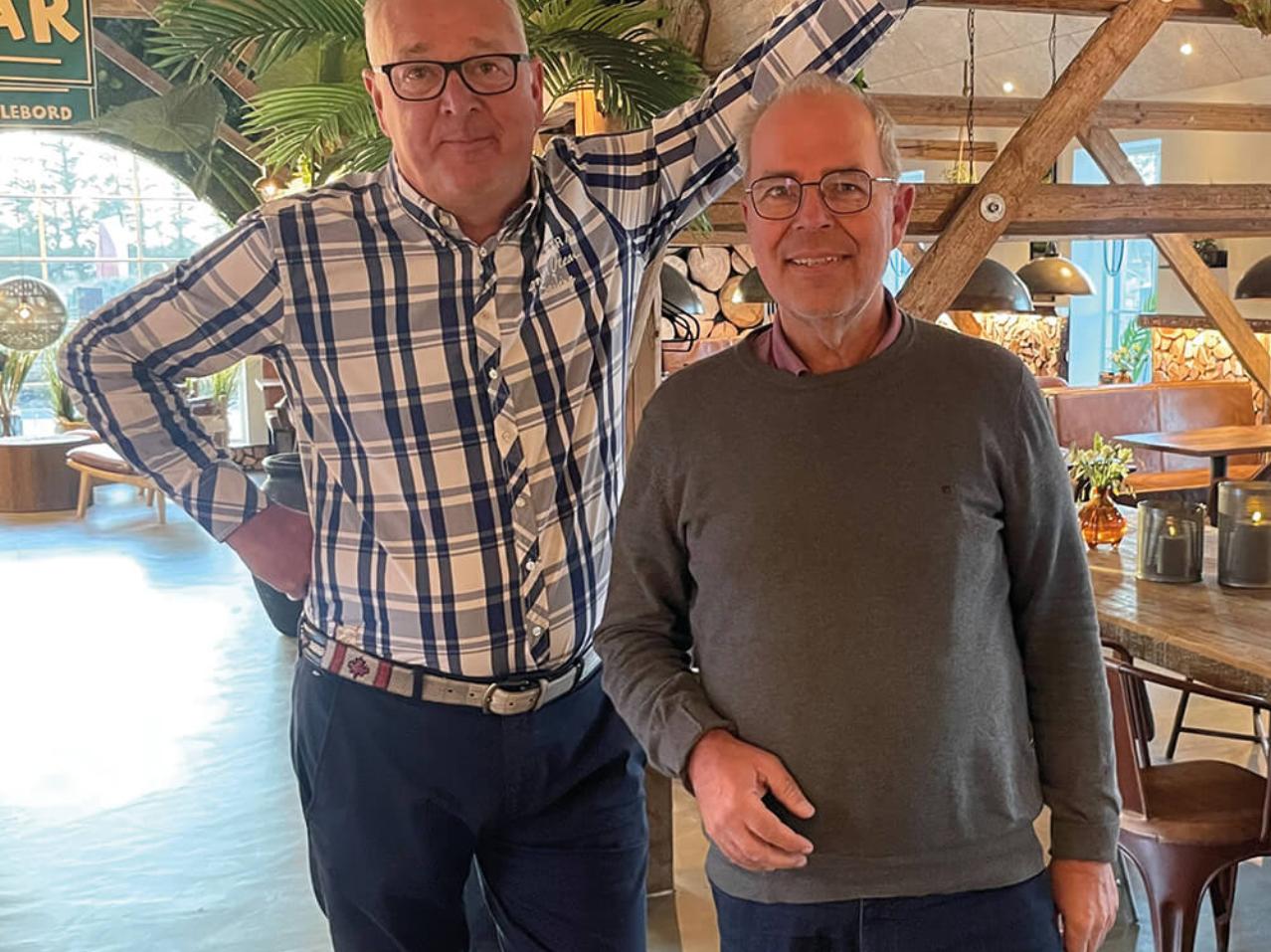 Helle und einladende Café-Einrichtung mit rustikalen Holztischen, modernen Dekorationen und großen Fenstern, die eine gemütliche Atmosphäre mit Blick auf die Natur schaffen.